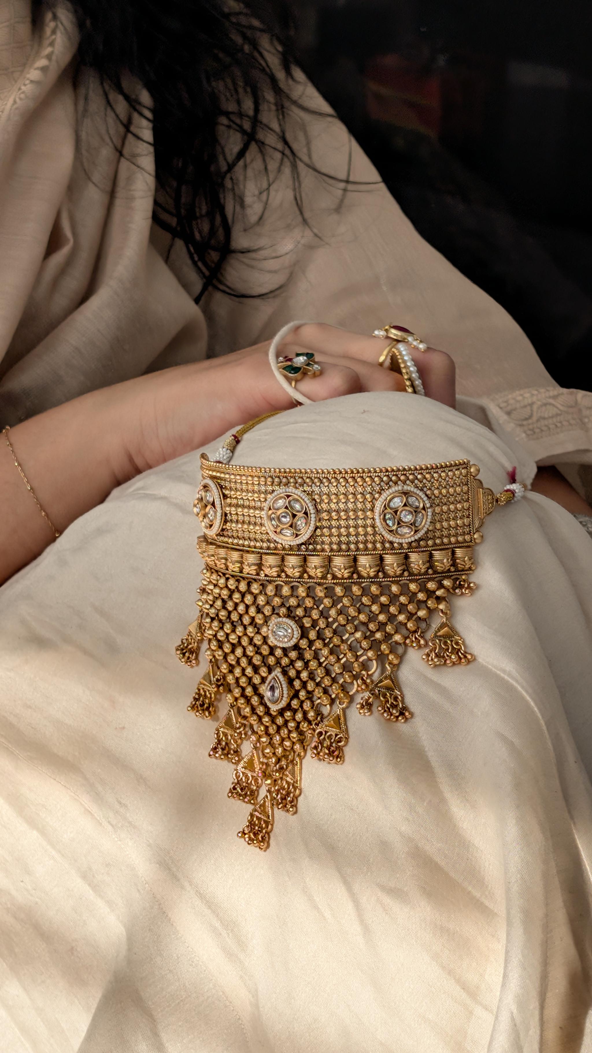 A bride holding an antique gold necklace in the Outbox House studio